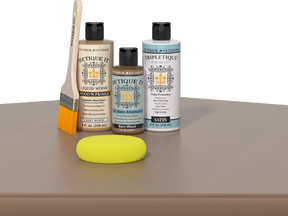 Retique It Barn Wood Kit displayed on a tabletop with the Light Wood Liquid Wood Wood'n Primer bottle, Barn Wood Gel Stain Alternative bottle, and Satin Tripletique topcoat bottle arranged together. A natural wood-handled paintbrush stands beside the products, and a yellow sponge rests in front of the bottles. The product labels face forward against a simple dark background.