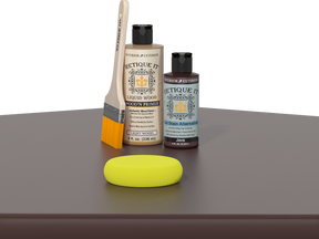 Retique It® Java Kit with Light Wood’n Primer, Java Gel Stain Alternative, paintbrush, and yellow sponge on a dark wood tabletop.