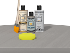 Retique It® Weathered Wood Multipurpose Kit contents with Light Wood Liquid Wood primer, Weathered Wood gel stain alternative, PolyTique It® matte exterior top coat, paintbrush, and yellow sponge displayed on a gray wood surface.