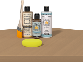 Retique It® Pecan Multipurpose Kit contents with Light Wood Liquid Wood primer, Pecan gel stain alternative, Tripletique matte interior top coat, paintbrush, and yellow sponge displayed on a wood surface.