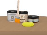 Retique It® Pecan Multipurpose Kit contents with Light Wood Liquid Wood primer, Pecan gel stain alternative, PolyTique It® matte exterior top coat, paintbrush, and yellow sponge displayed on a wood surface.