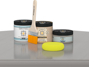 Retique It® Weathered Wood Multipurpose Kit contents with Liquid Wood primer, Weathered Wood gel stain alternative, Tripletique gloss interior top coat, paintbrush, and yellow sponge displayed on a gray wood surface.