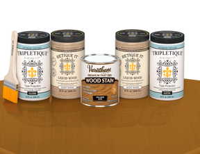 64 oz Retique It Liquid Wood kit with Golden Oak stain, gloss Tripletique topcoat, and a paintbrush on a matching finished tabletop.