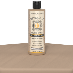 Retique It® Liquid Wood Wood'n Primer in Light Wood, 8 fl oz, showing the primer applied on a wooden table surface.