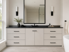 Modern bathroom with a white double vanity, black countertop and hardware, large black-framed mirror, and wall sconces.