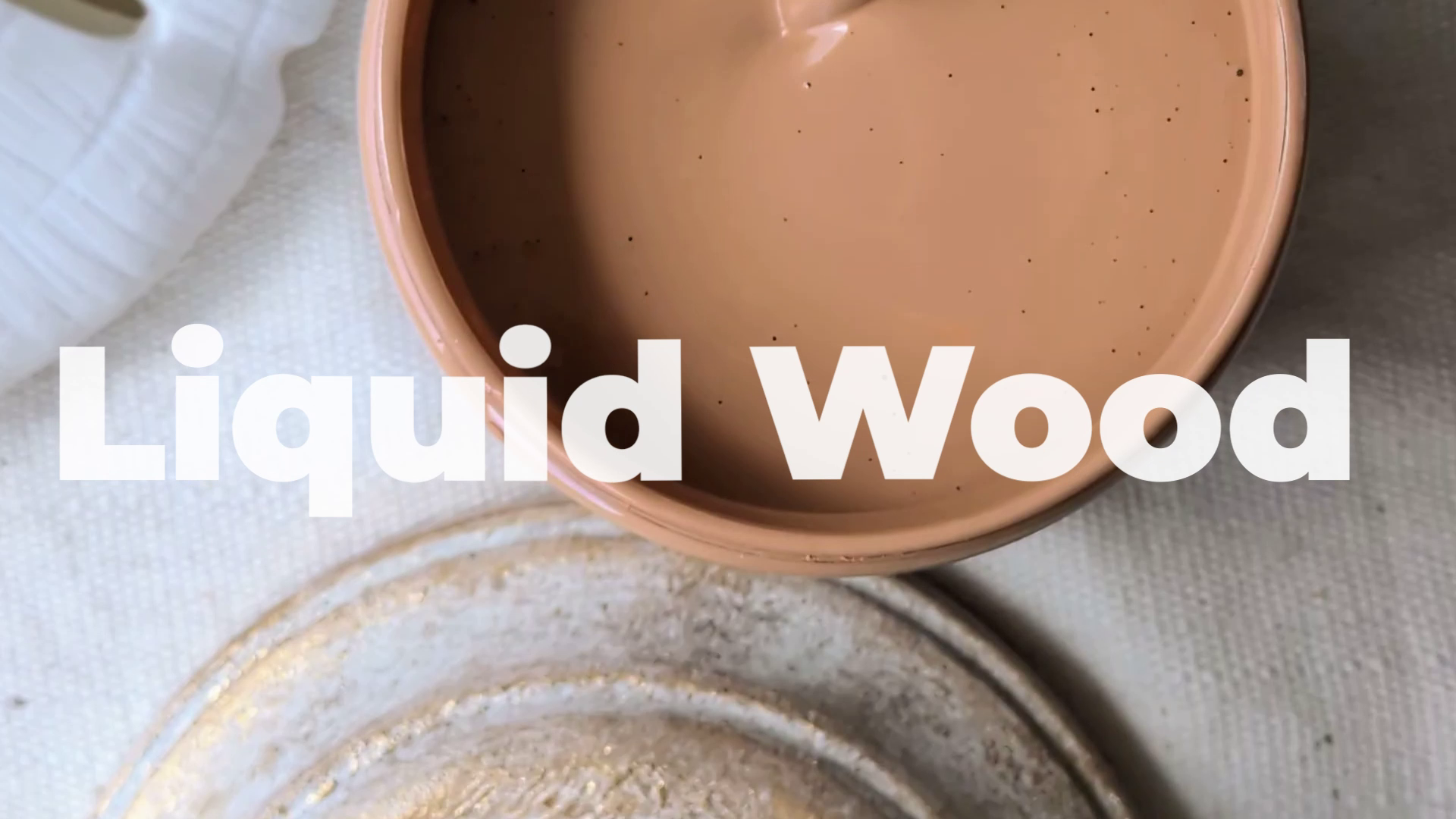 Ceramic bowl with 'Liquid Wood' text overlay on a textured surface